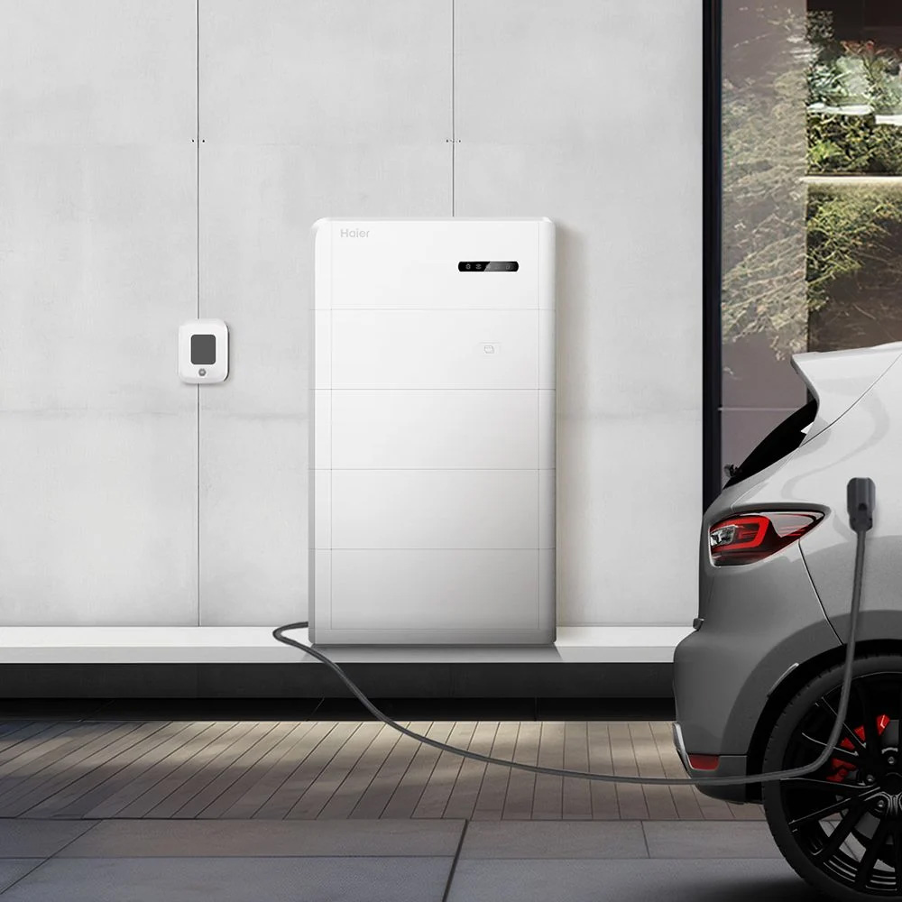 Haier Smart Cube Speichersystem an einer Wand. Das Kabel des Systems geht zum Auto. Haier Smart Cube Speichersystem; angesteckt an einer Schuko-Steckdose; daneben ein Auto zur Darstellung